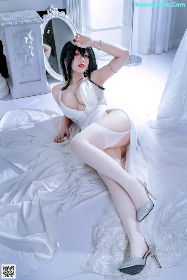 A woman in a white lingerie sitting on a bed.