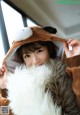 A woman in a brown bear costume holding a fluffy white dog.