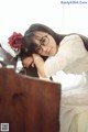 A woman in a white dress sitting at a piano.