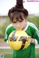 A young girl holding a soccer ball on a field.