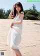 A woman in a white dress standing on a beach.