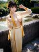 A woman in a yellow and white kimono posing for the camera.