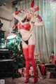 A woman in a red and black lingerie posing in front of a Christmas tree.